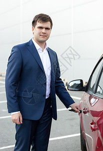 英俊年轻商人开汽车门的肖像图片
