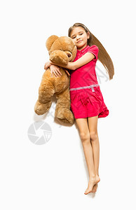 从躺在地板上拥抱大泰迪熊的可爱女孩顶部被孤立图片