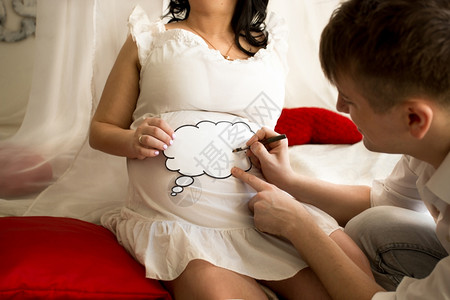 年轻男子在妻和上持有复制空间标志的年轻男子怀孕肚图片
