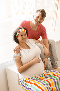 快乐的怀孕夫妇抱和看着相机的肖像图片