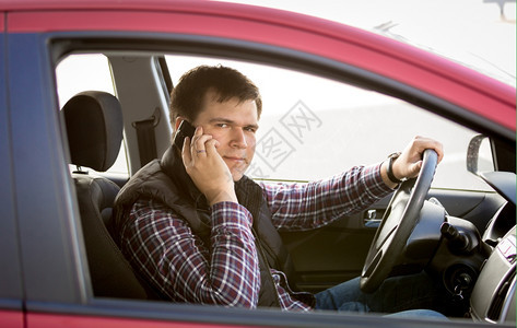 男驾驶员汽车时通过电话交谈的近镜肖像图片