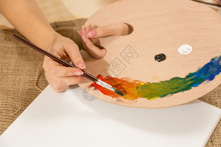 年轻女艺术家在托盘上涂漆时刷油的宏观照片图片