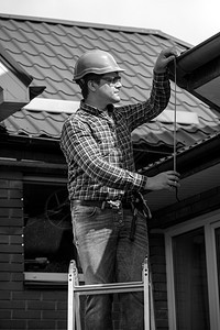 修复房屋顶的青年工人黑白画像图片
