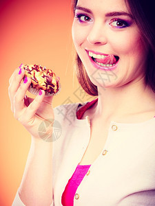面包甜食和人的概念女享受蛋糕舔嘴唇的橙色背景图片