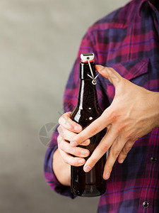 青年男子在灰色背景上拿着啤酒瓶图片