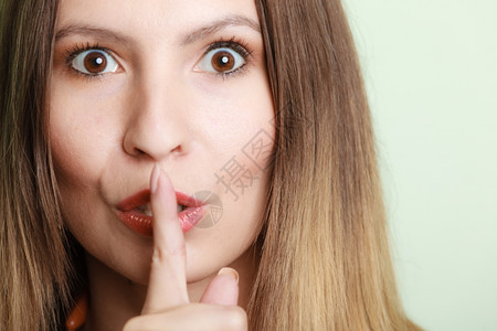 妇女眼睁地要求沉默或秘密用手指在嘴唇上低语手势图片
