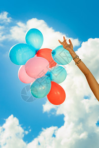 女手拿着彩色气球云的天空背景户外图片