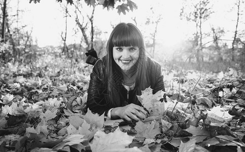 在秋林中躺树叶上的微笑着女人黑白画像图片