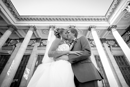 黑人和白的肖像刚结婚的夫妇亲吻与经典建筑的接吻图片