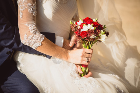 新郎抱娘握着婚礼花束的紧贴照片图片
