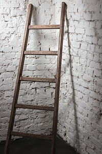 工作室照片靠着白砖墙的旧木梯子图片