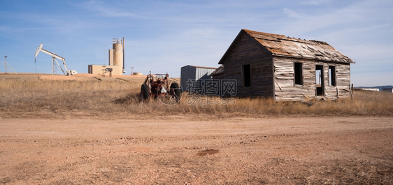 一辆废弃的拖拉机和小木屋坐在一个裂缝油泵罐的前方图片