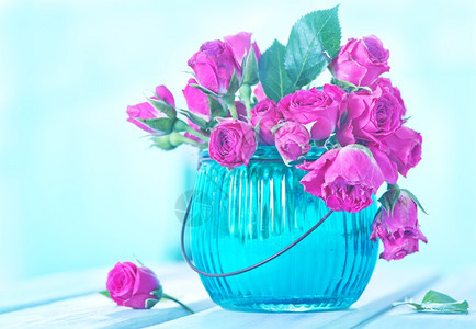 一群小粉红玫瑰花瓶在木制桌子上的玻璃花瓶里图片