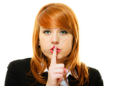 女商人红头发孩要求沉默或保密用手指着嘴唇的沉默手势图片