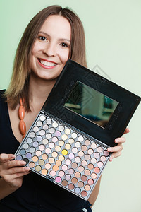 化妆美容程序和概念女拥有专业调色板化妆应用绿色背景图片