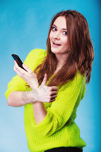 女少在手机上发短信使用智能手机读短手举势用蓝色图片