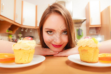 女人看着美味的蛋糕上面有甜的奶油和水果喜欢贪食的概念女人看着美味的甜饼图片