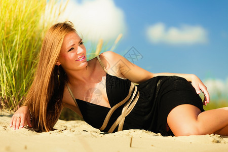 暑假白天自由时间的概念坐在海滩边的女子日光浴图片