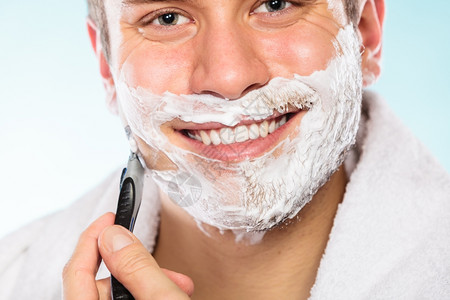 健康美貌和皮肤护理概念漂亮的年轻胡须男子脸上涂着泡沫部刮胡须蓝色背景的剃胡刀图片
