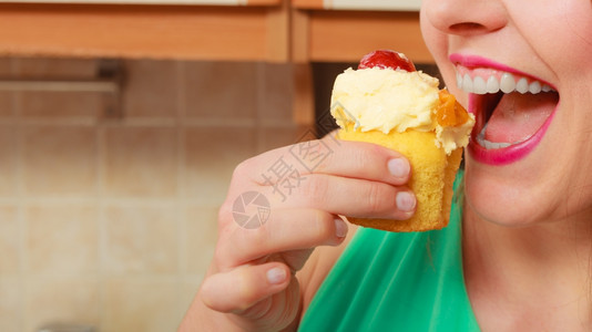 女人吃着美味的蛋糕上面有甜的奶油和水果美味的贪食观念女人吃着美味的甜饼图片