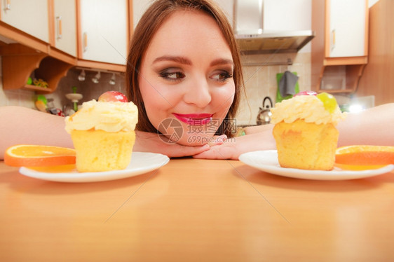 女人看着美味的蛋糕上面有甜的奶油和水果喜欢贪食的概念女人看着美味的甜饼图片