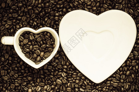 咖啡时间白色杯子和茶碟以烤咖啡豆背景为心形的白杯子和碟图片
