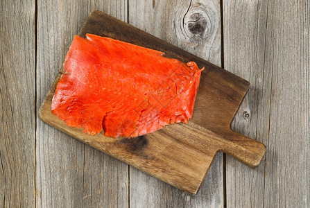 木质服务器板上薄切的冷烟熏红鲑鱼顶端视图下面有生锈的木头图片