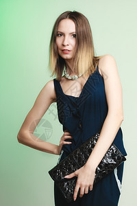 年轻时尚髦的女孩拿着黑皮包穿绿色时装和女美貌工作室拍摄图片