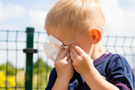 悲伤的小男孩哭泣不快乐的孩子在户外用组织擦他的眼睛图片