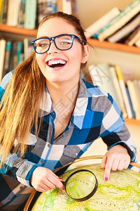 教育旅行和地理概念年轻聪明的女学生在有地球和放大镜的图书馆用蓝色眼镜和放大图片