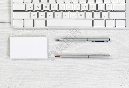 白桌面上部分键盘空白名片堆和银笔的图像横向版式图片
