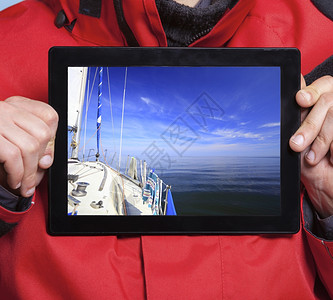 男手握着游艇帆船的照片紧握着皮达的男手水们展示了屏幕平板电脑触摸梦想着游艇航行技术和游轮图片