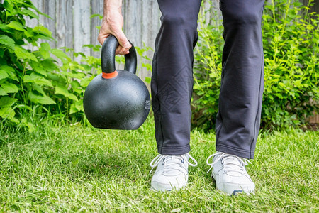 在后院绿草上与重铁竞争的kttbell62lb8公斤一起健身户外健身概念图片