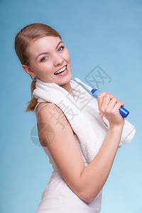年轻有趣的女孩唱歌给牙刷她的白在蓝色上玩耍每日牙科护理工作室拍摄图片
