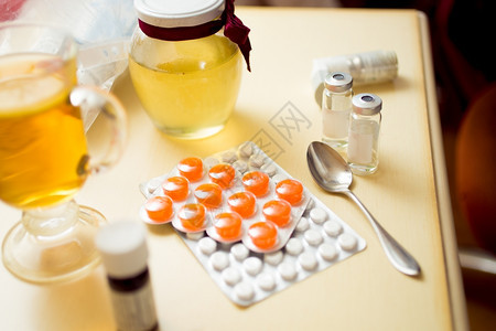 床边桌上的泡和蜂蜜罐中药片的近照图片