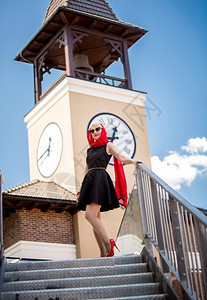 穿着黑裙子和红围巾的美丽优雅女子假扮在旧街上面对大塔钟图片