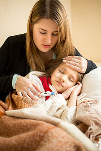 年轻母亲在床上拥抱生病女孩的肖像图片