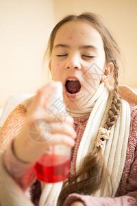 使用喷雾洒喉咙痛的小女孩肖像图片