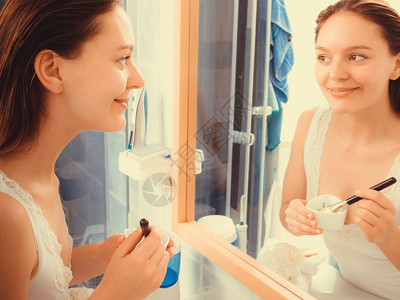美容护皮肤化妆品和健康概念年轻女在浴室用泥脸部涂用面粘土罩顶着刷子和碗图片