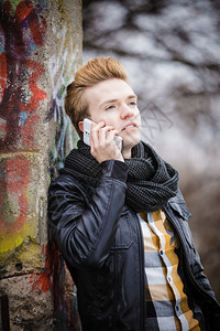 青年时装男在户外使用智能手机在移动电话上交谈图片