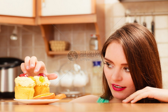 女人吃甜的蛋糕奶油和水果上面的和手指美味贪食的概念甜图片