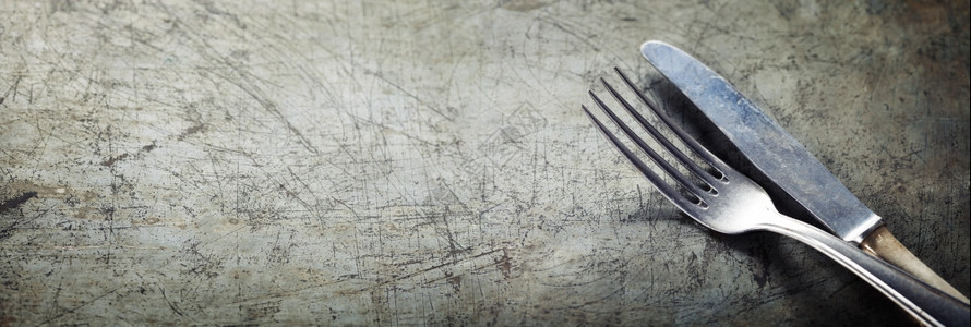 在具有复制空间的生锈老旧背景上用餐叉和刀图片