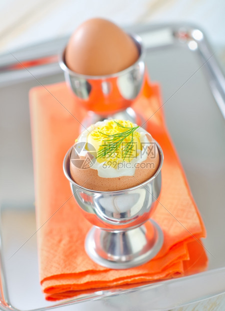 橘色餐巾纸上铁杯里煮熟的鸡蛋图片