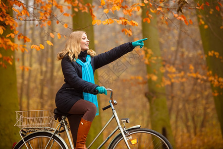 美少女在秋天户外公园骑着自行车背景图片
