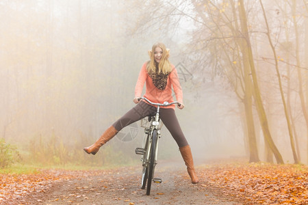 快乐女子在户外秋季公园骑着自行车图片
