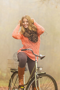 穿着套头毛衣的女人在森林里骑着自行车图片