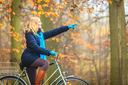 美女在秋天户外森林里骑着自行车图片