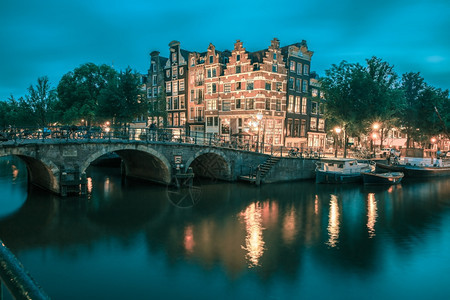 阿姆斯特丹运河桥梁和典型房屋船只和自行车的夜间城市景色荷兰图片