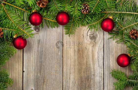真正的Fir树枝和带红饰物的锥子在形成边界的生锈木板上圣诞节的概念图片