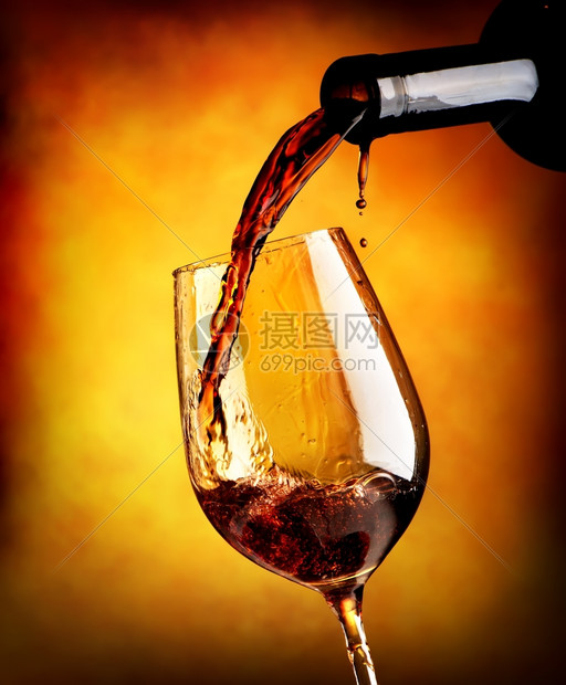 红酒倒在橙色背景的葡萄酒杯中图片